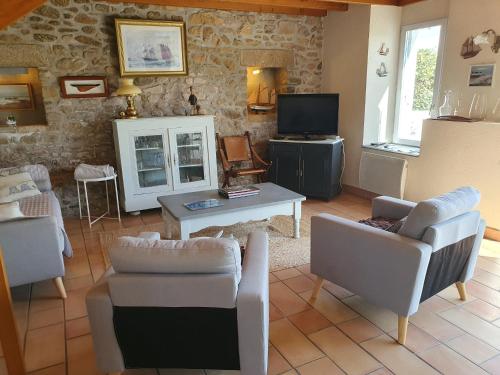 - un salon avec des chaises, une table et une télévision dans l'établissement Jolie maison vue mer 6 personnes à Plouguerneau, à Plouguerneau