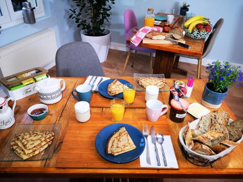ein Holztisch mit Tellern voller Essen darauf in der Unterkunft Chambres d'hôtes "Le Clos de la Baie" in Paimpol