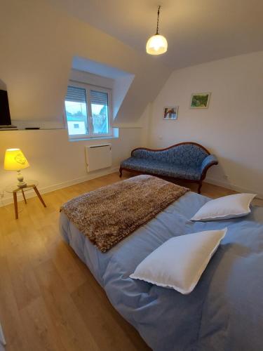 a bedroom with a bed and a couch and a window at Chambre Alice in Saint-Pair-sur-Mer