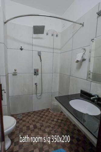 Un baño con ducha, lavabo e inodoro. en Hotel Chithrapuri, en Parli
