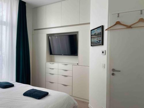 - une chambre blanche avec une télévision et un lit dans l'établissement Entire Apartment Jardin du Luxembourg, à Paris