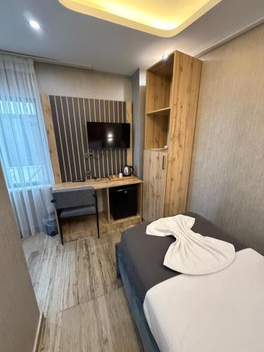 a bedroom with a bed and a desk with a television at world say hotel in Bostaniçi