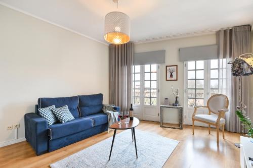a living room with a blue couch and a table at Casa do Chafariz Family Ap by Sé Apartamentos in Braga