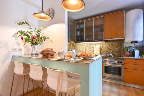 a kitchen with a breakfast bar with white chairs at Casa do Chafariz Family Ap by Sé Apartamentos in Braga