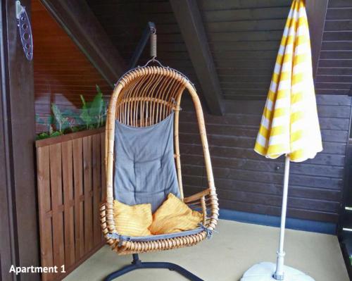 einen Korb-Schaukelstuhl auf einer Veranda mit einem Regenschirm in der Unterkunft Ferienwohnungen Vesteblick in Dörfles