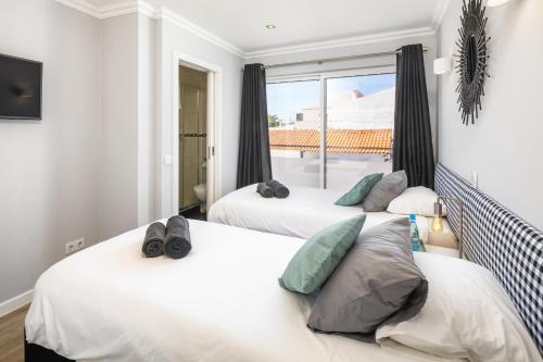 two beds in a room with a window at Penthouse Milhafre in Benagil
