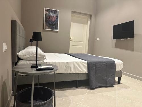 a bedroom with a bed and a table with a tv at Sunset Palace Guesthouse in Reggio Calabria
