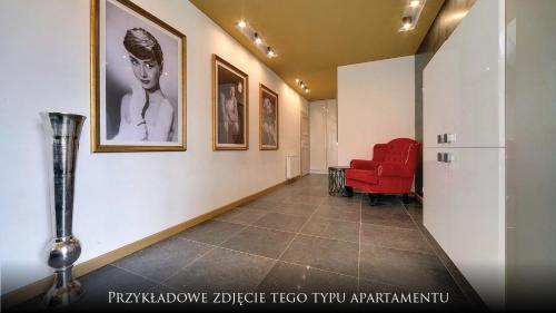 a hallway with a red chair and pictures on the wall at Norweska Dolina Family&Pet-friendly Resort in Szklarska Poręba