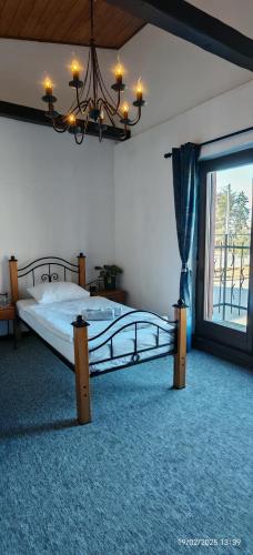a bedroom with a bed with a chandelier and a window at Hotel Plzeňský Dvůr in Frýdek-Místek
