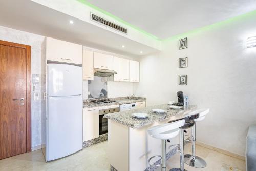 a white kitchen with a counter and a refrigerator at Royal Deluxe Silver - Marrakech, Luxe Pool View in Marrakech