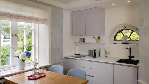 a kitchen with white cabinets and a wooden table at Benen-Diken-Hof in Keitum