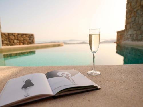 an open book and a glass of wine on a table at Mykonos Rocks Villas & Suites in Mýkonos City