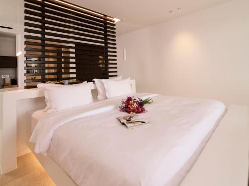 a white bedroom with a large white bed with flowers on it at Mykonos Rocks Villas & Suites in Mýkonos City