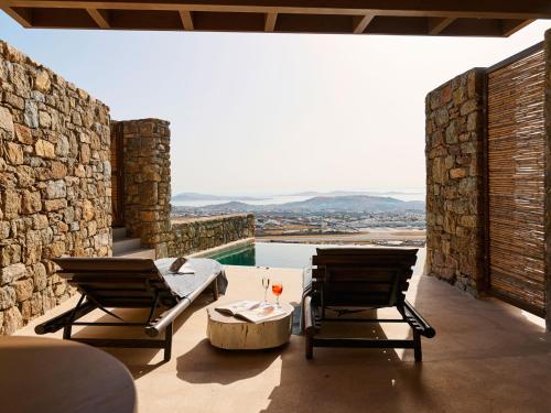 a patio with two chairs and a table and a pool at Mykonos Rocks Villas & Suites in Mýkonos City