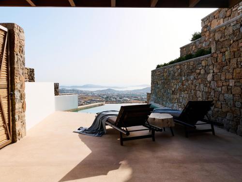 a balcony with two chairs and a pool at Mykonos Rocks Villas & Suites in Mýkonos City