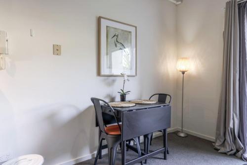 a room with a table with chairs and a lamp at Stylish studio Apt near AIS and GIO Stadium - Hosted by Canstay in Belconnen