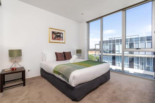 a bedroom with a large bed and large windows at Modern 3BR Home 5 mins away from Parliament House - Hosted by Canstay in Barton