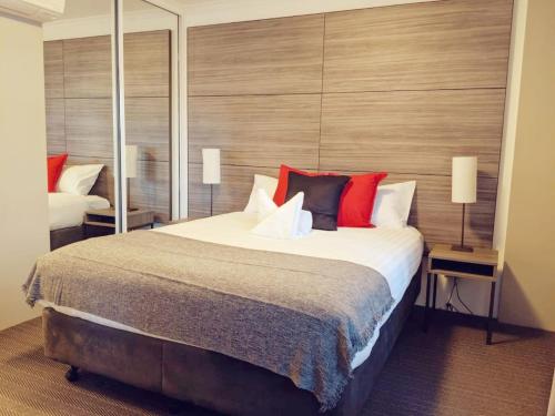 a bedroom with a large bed with red pillows at Exquisite Apartment at Citys Doorstep - Hosted by Canstay in Canberra