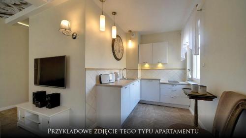 a kitchen with white cabinets and a tv on the wall at Norweska Dolina Family&Pet-friendly Resort in Szklarska Poręba
