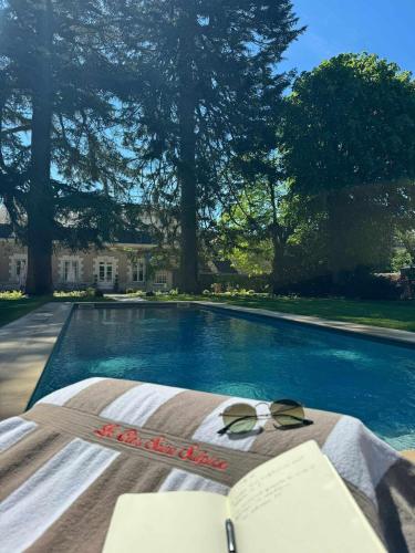 une paire de lunettes de soleil posée sur une table à côté d'une piscine dans l'établissement Clos Saint Sulpice, à Fossé
