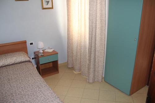 a bedroom with a bed and a table and a window at Hotel Geranio Rosso in Stintino