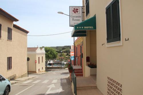 a street in a town with a sign on a building at Hotel Geranio Rosso in Stintino