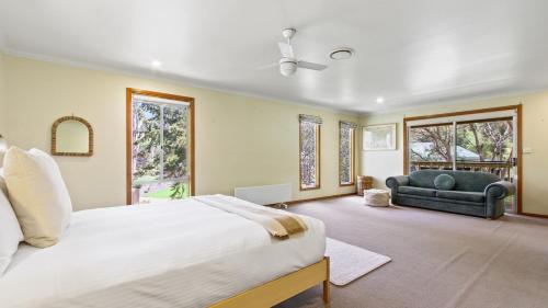 a bedroom with a bed and a couch and windows at Casa Mia Metung in Metung