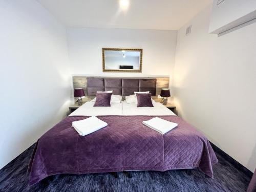 a bedroom with a large bed with a purple blanket at Hotel Sobieraj in Krzeszyce