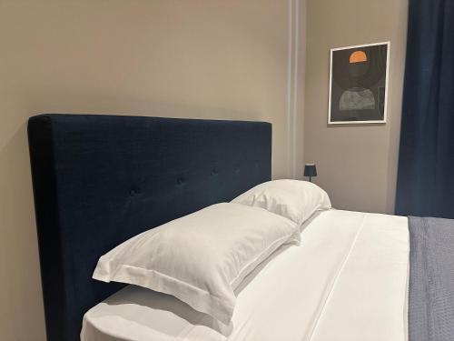 a bed with a blue headboard and two pillows at Sunset Palace Guesthouse in Reggio Calabria