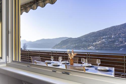 a table on a balcony with a view of the ocean at Elegant, Lugano Lake View, pool and private parking in Brusino Arsizio