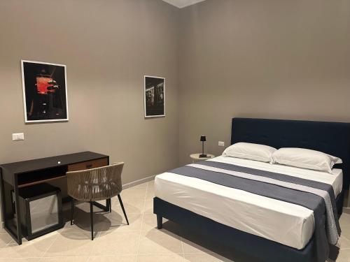 a bedroom with a bed and a table and a desk at Sunset Palace Guesthouse in Reggio Calabria