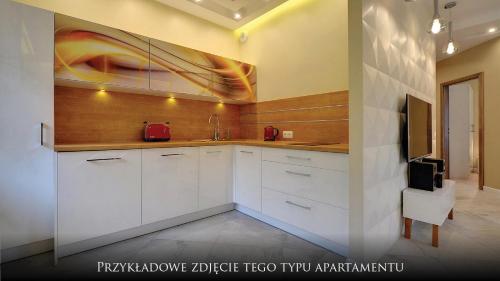 a kitchen with white cabinets and a painting on the wall at Norweska Dolina Family&Pet-friendly Resort in Szklarska Poręba