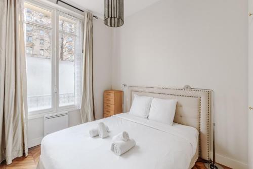 une chambre avec un lit blanc avec deux serviettes dessus dans l'établissement Charmant Appartement 4P- Face ARC de Triomphe, à Paris