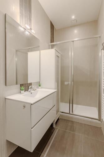 une salle de bain blanche avec un lavabo et une douche dans l'établissement Charmant Appartement 4P- Face ARC de Triomphe, à Paris