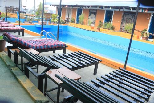 a pool with benches and a table and a swimming pool at Shivas Hippies Colony in Sauraha