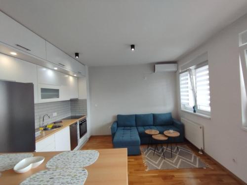 a living room with a blue couch and a kitchen at Astra apartman BL in Banja Luka