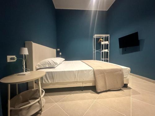 a blue bedroom with a bed and a table at Sunset Palace Guesthouse in Reggio Calabria