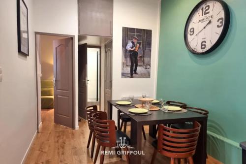 une salle à manger avec une table et une horloge au mur dans l'établissement The Wall City Center Terrace & Parking 4 Guests, à Honfleur