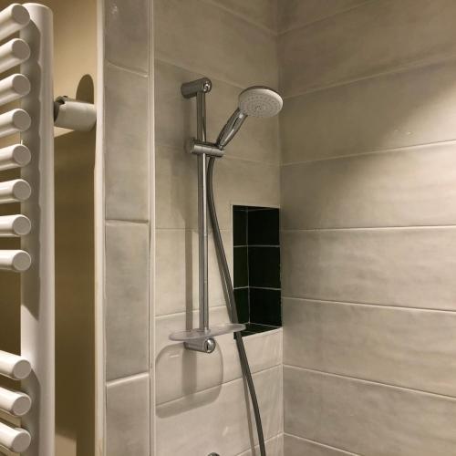 une douche avec pommeau de douche dans une salle de bain dans l'établissement Maison d'Alice - Maison indépendante en centre-ville avec parking, à Cluny