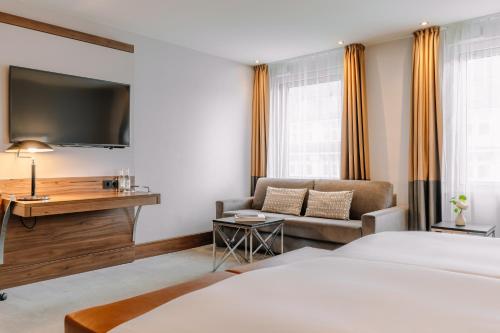 a hotel room with a bed and a couch at Reichshof Hotel Hamburg in Hamburg