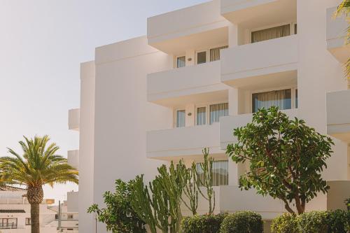 an apartment building with trees in front of it at Aparthotel Novo Mar in Paguera
