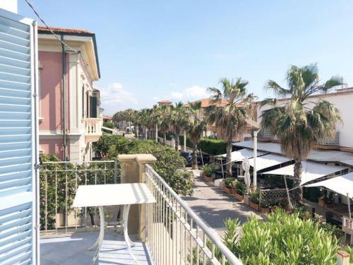 a balcony with a bench and palm trees and buildings at Zì Maria in Marina di Cecina
