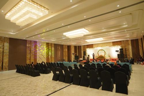 a large room with chairs and a stage with a microphone at Hotel Abhinandan in Mathura