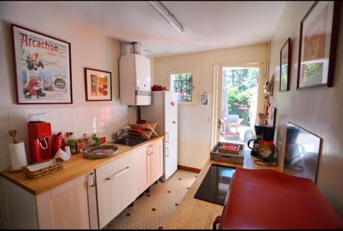 une cuisine avec un réfrigérateur blanc et une table dans l'établissement Maison des Pins, à Arcachon