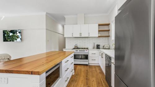 a kitchen with white cabinets and a wooden counter top at The Victorian Grove in Metung