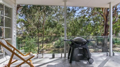 a stroller on a porch with a view of trees at The Victorian Grove in Metung