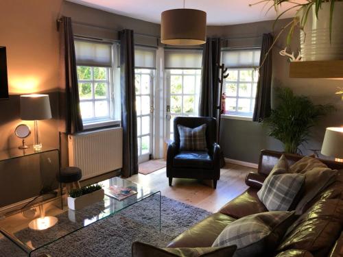 a living room with a couch and a chair at Loch Lomond Hideaways- Luxury Cabins with Jacuzzis in Drymen