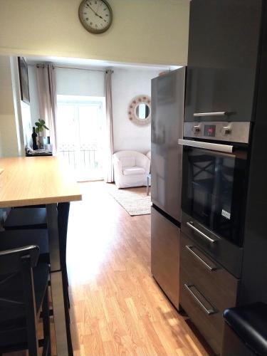 Il comprend une cuisine équipée d'un réfrigérateur en acier inoxydable et d'une horloge murale. dans l'établissement Triangle d'OR bel appartement 2ch lumineux et calme, à Bordeaux