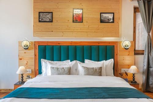 a bedroom with a large bed with a blue headboard at SaffronStays Bagh Kufri in Kūfrī