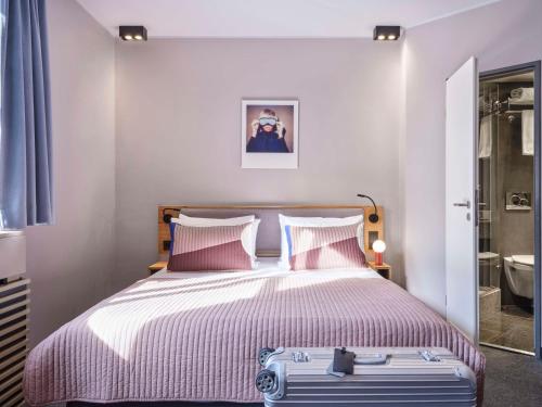 a bedroom with a bed with a suitcase next to it at Flemings Hotel Frankfurt-Central in Frankfurt/Main